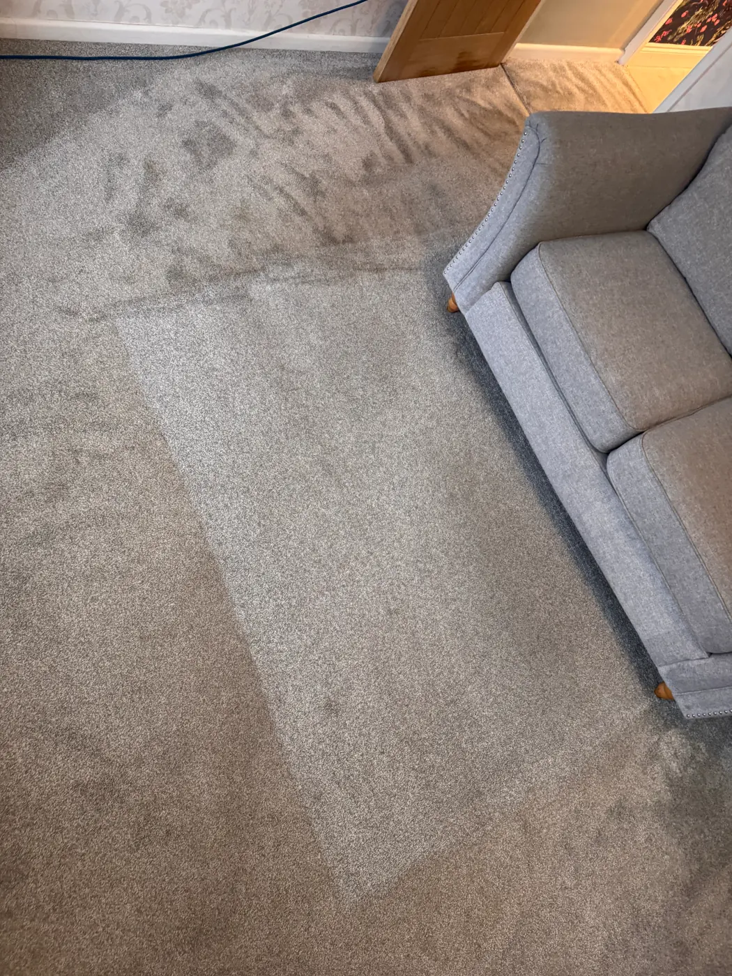 Clean grey carpet with extraction lines beside a grey sofa