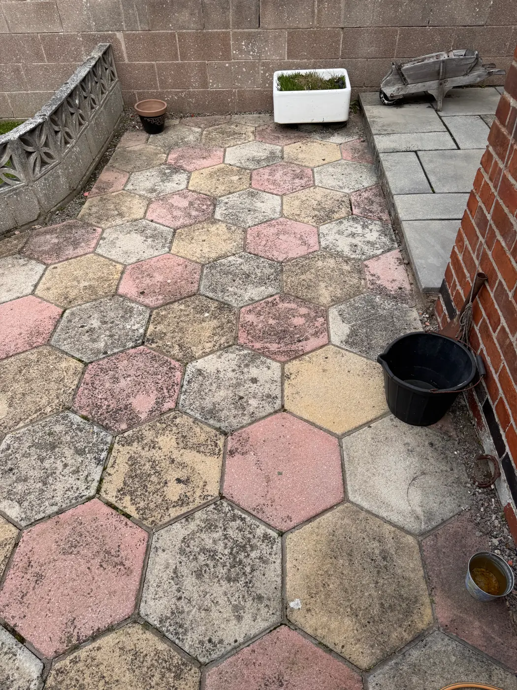 Hexagonal patio paving facing the boundary wall before cleaning
