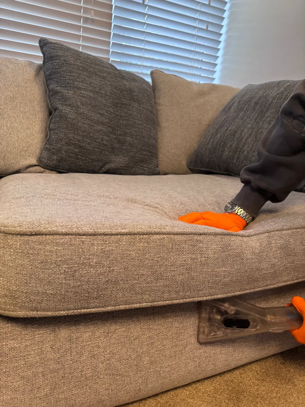 Me cleaning a pale fabric sofa with an extraction tool